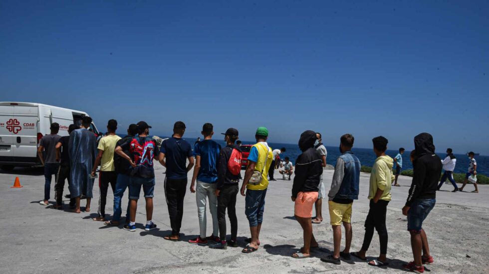 Migrantes hacen cola ante una furgoneta de Cáritas para recoger bolsas de comida en Ceuta.
