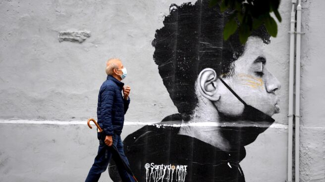 Un hombre camina con mascarilla el primer día sin mascarilla obligatoria en exteriores. Un hombre camina con mascarilla el primer día sin mascarilla obligatoria en exteriores. Lo hace delante de una obra del artista @Sentydo ART en una campaña dedicada a los besos sin mascarillas.