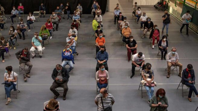 Varias personas esperan tras recibir la vacuna en el pabellón de deportes Paco Paz, en Orense.