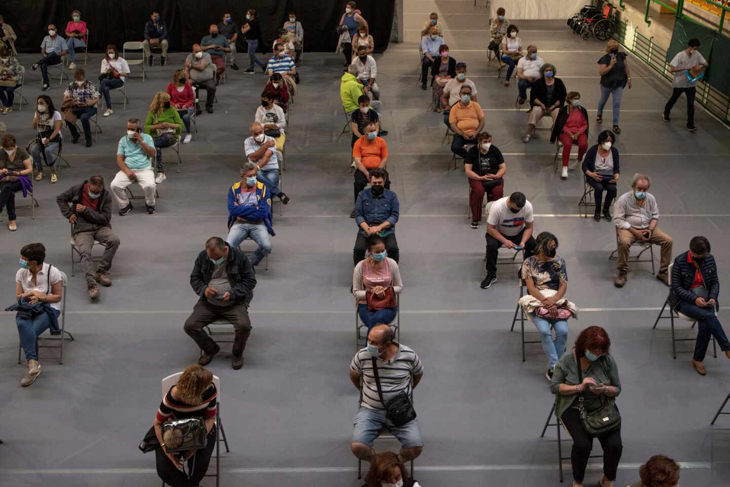 Varias personas esperan tras recibir la vacuna en el pabellón de deportes Paco Paz, en Orense.