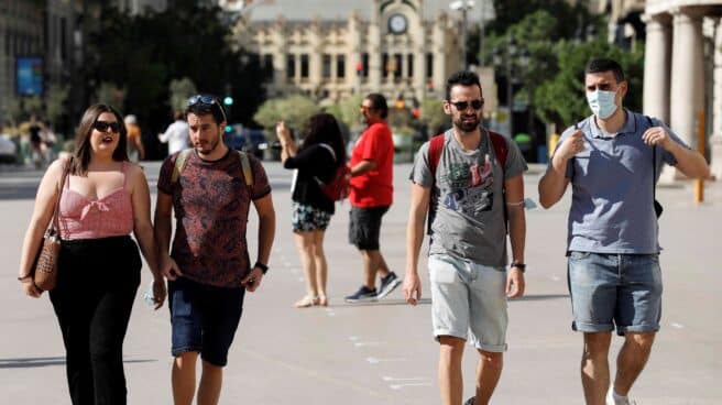 Varias personas caminan con y sin mascarillas por la calle en Valencia.