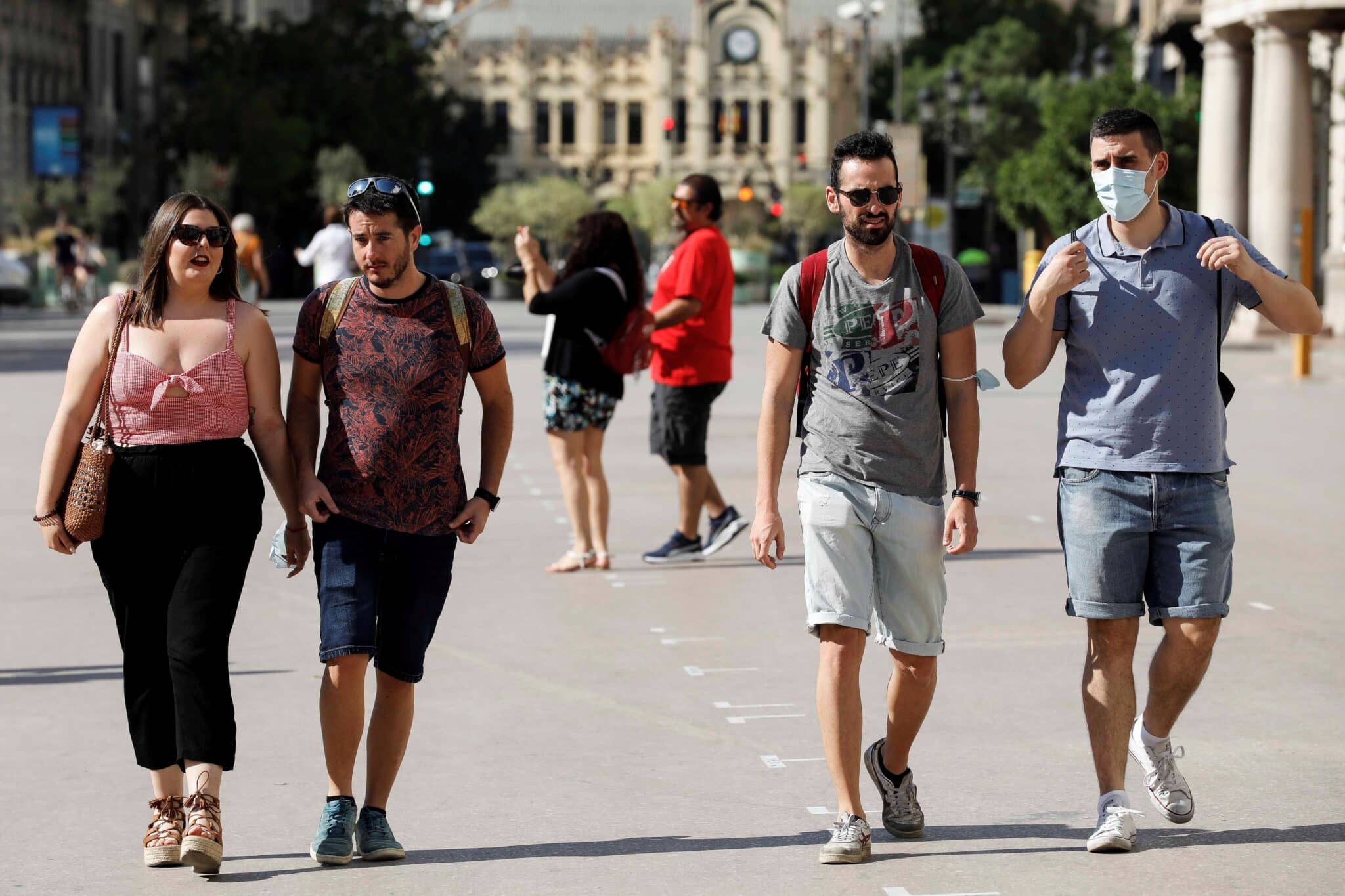 Varias personas caminan con y sin mascarillas por la calle en Valencia.