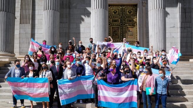 Medio centenar de organizaciones feministas convocan este sábado movilizaciones contra la Ley Trans Varias personas y demás autoridades posan con banderas trans en las escaleras del Congreso