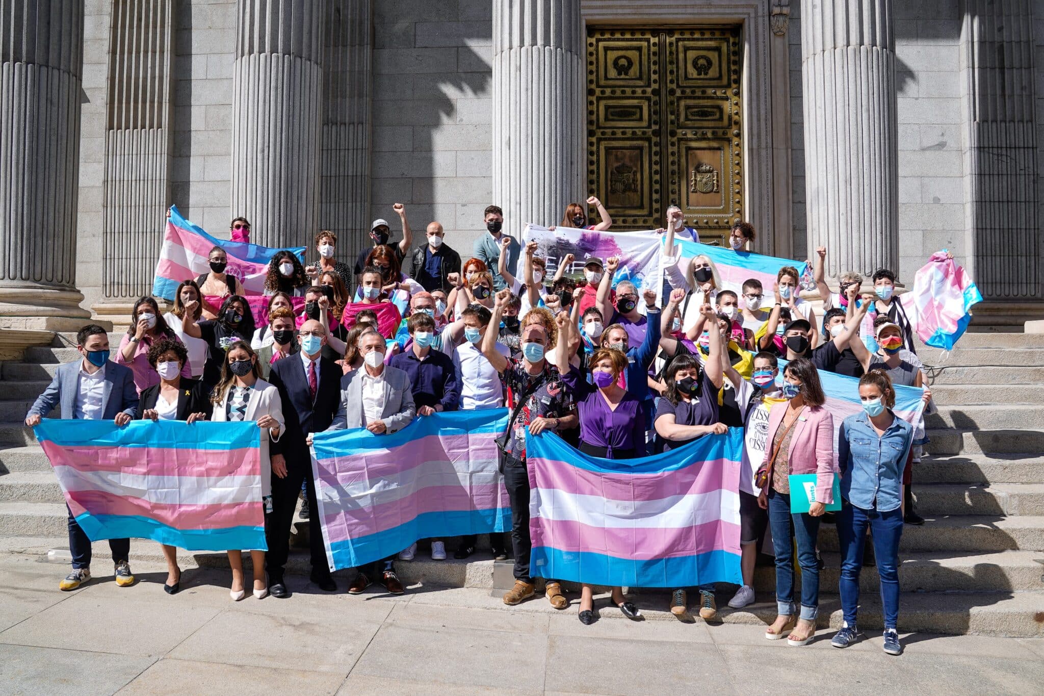 Varias personas y demás autoridades posan con banderas trans en las escaleras del Congreso