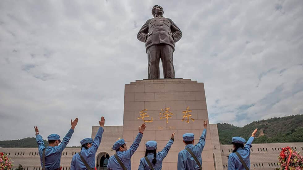 Visitantes con el uniforme del ejército rojo alzan sus manos frente al monumento del fundador de la República Popular China Mao Zedong.