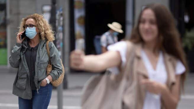 mascarillas-fin-uso-obligatorio Una chica se hace un selfie en la Puerta del Sol de Madrid ante una mujer con mascarilla.