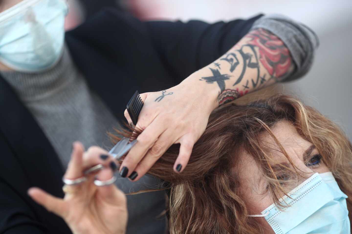 Una peluquera corta el pelo a una mujer .