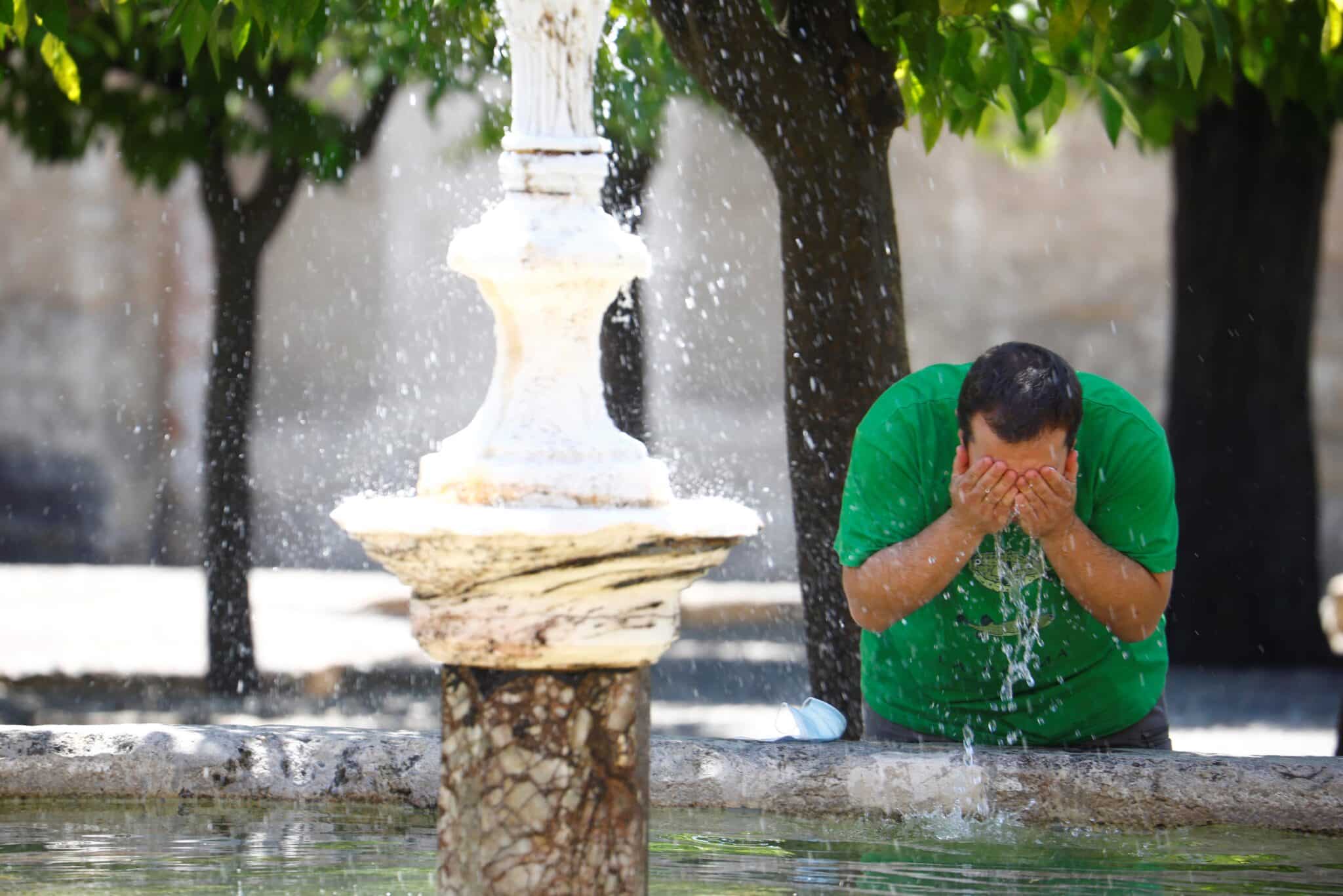 Un hombre se refresca en Córdoba.