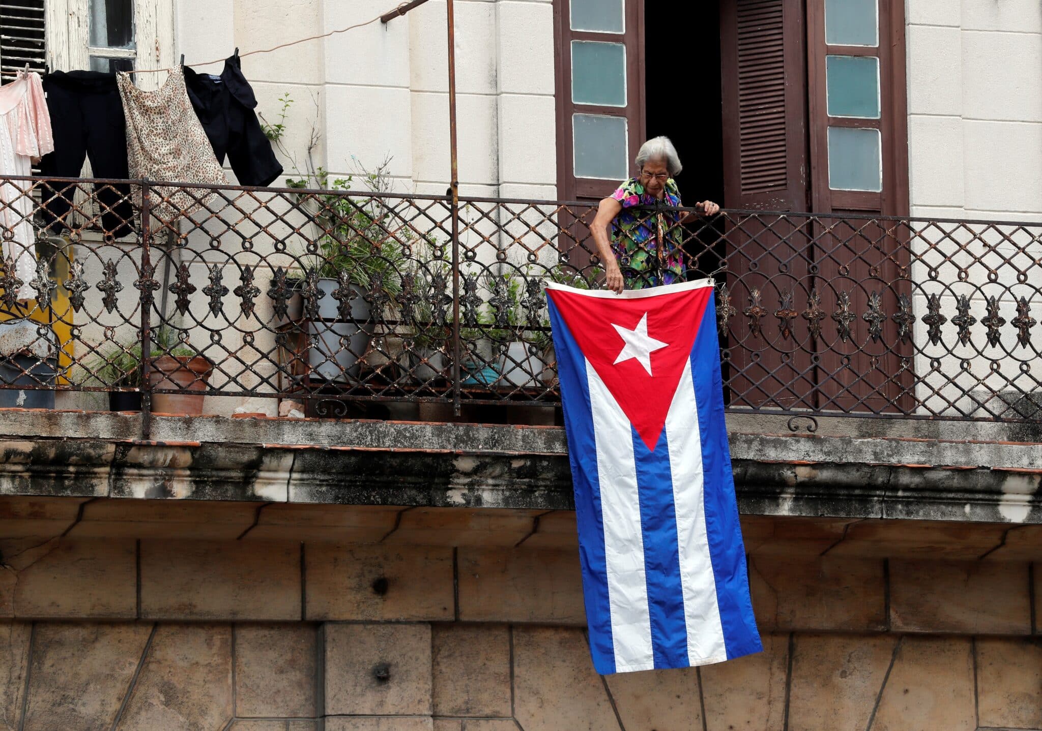 Una mujer en un balcón coloca la bandera cubana en La Habana