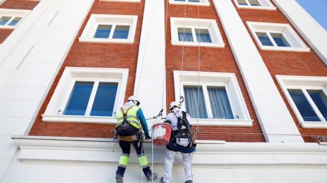 Dos operarios de obras, pintan parte de la fachada del edificio España.