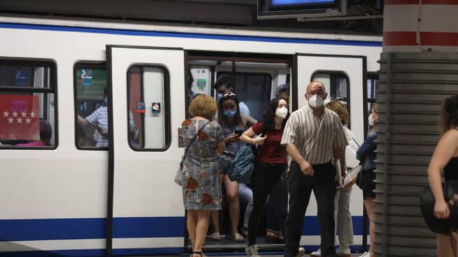 Pasajeros con mascarilla salen de un vagón en la estación de Metro de Atocha.