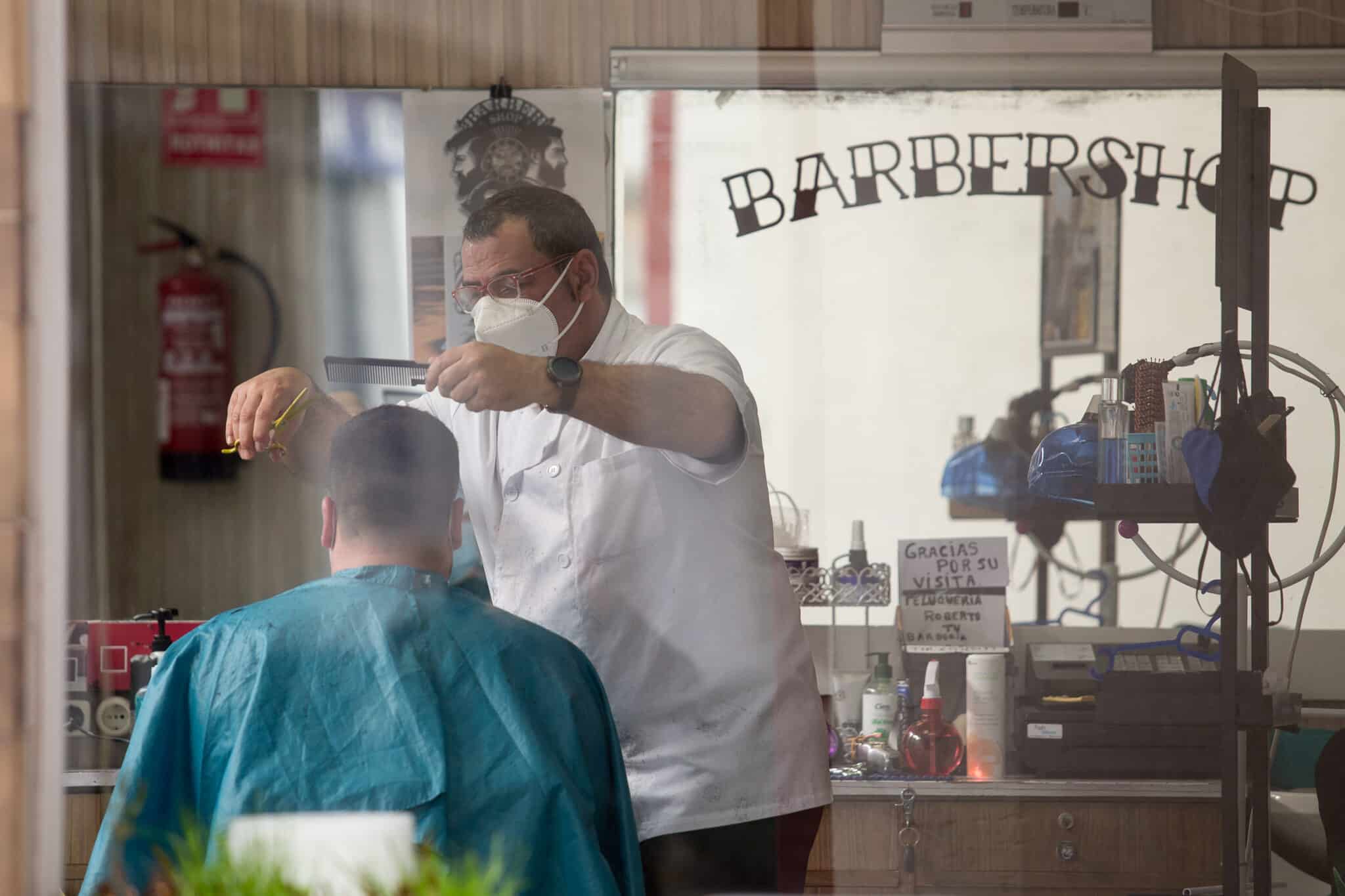 Un peluquero atiende a un cliente en el municipio gallego de Guitiriz, en Lugo, Galicia.
