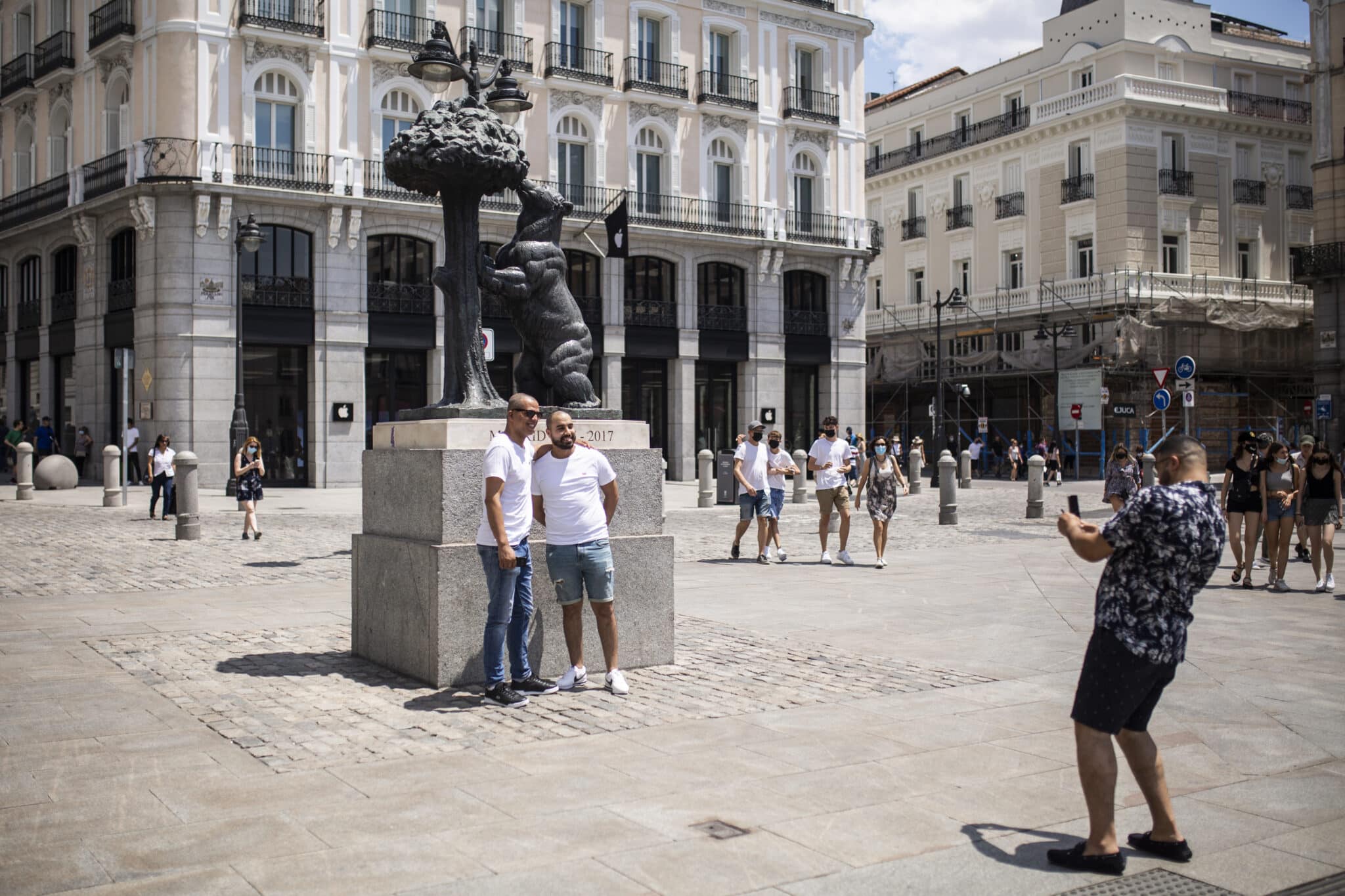 Un hombre toma una foto a otros dos, sin mascarilla en la Puerta del Sol.