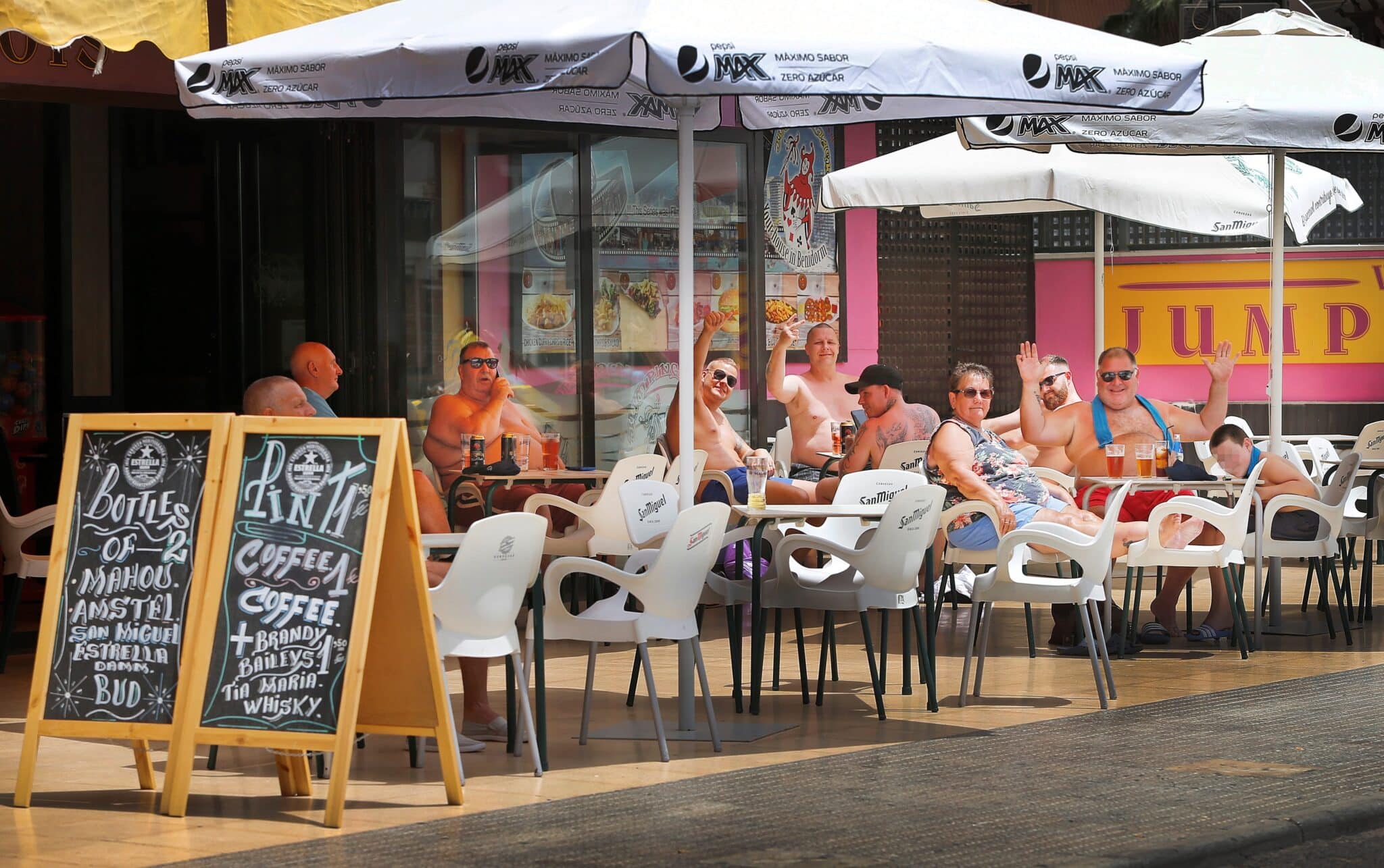 Varios turistas saludan al fotógrafo sentados en una terraza de Benidorm.