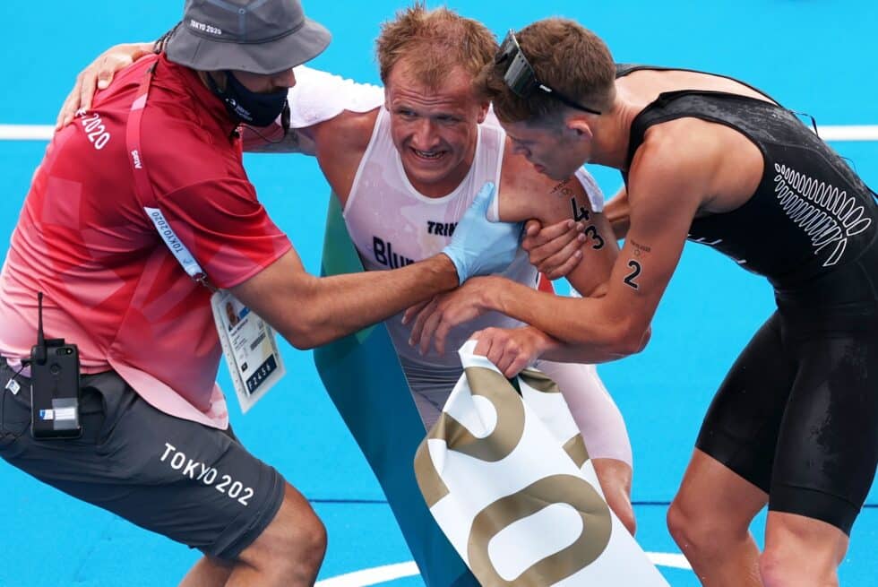 El ganador de la prueba de triatlón, Kristian Blummenfelt, ayudado nada más cruzar la meta