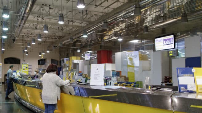 Una usuaria realiza un trámite en una oficina de Correos en el centro de Madrid.