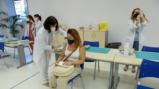 Por qué duele el brazo después de la vacuna contra el covid: moderna y pfizer Fotografía de una mujer joven siendo vacunada en un centro sanitario por una enfermera