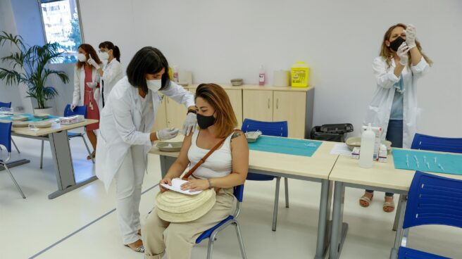 Fotografía de una mujer joven siendo vacunada en un centro sanitario por una enfermera