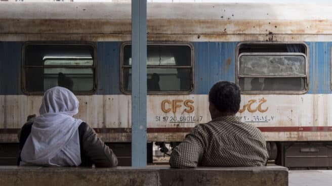 Dos hombres en la estación de Alepo frente a un tren abandonado