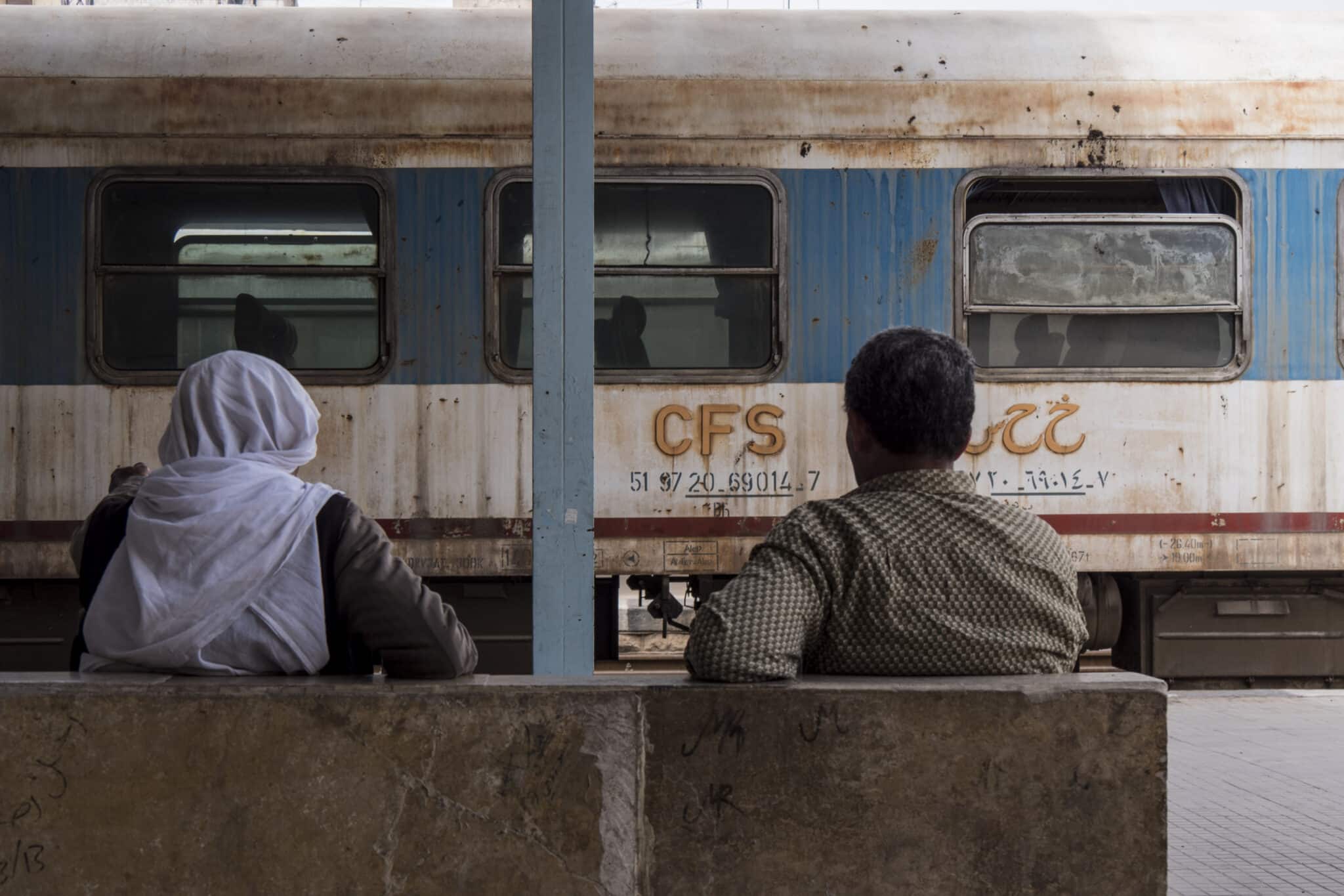 Dos hombres en la estación de Alepo frente a un tren abandonado