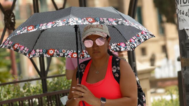 Una mujer se protege del sol con un paraguas.