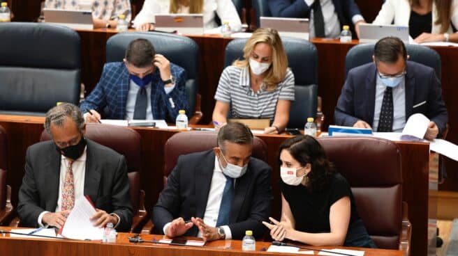 La presidenta de la Comunidad de Madrid, Isabel Diaz Ayuso (d) conversa con el consejero de Presidencia y Justicia de la Comunidad de Madrid, Enrique López , durante el pleno en la Asamblea de Madrid