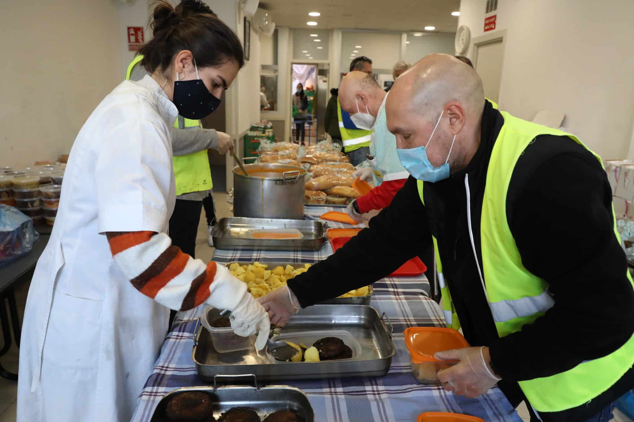 Una cocinera sirve comida varias raciones de comida a voluntarios