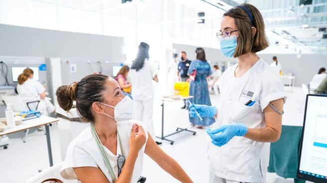 ¿Puedo ponerme la segunda dosis de la vacuna contra el covid en otra comunidad autónoma? Una mujer conversa con una enfermera mientras le vacuna en el Hospital público de emergencias Enfermera Isabel Zendal