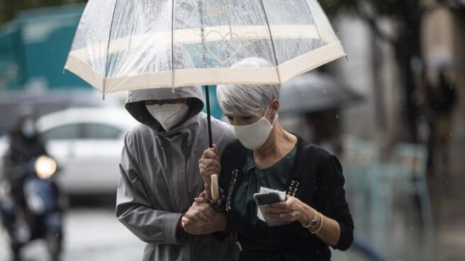 Dos personas se protegen de la lluvia bajo un paraguas, en Sevilla.