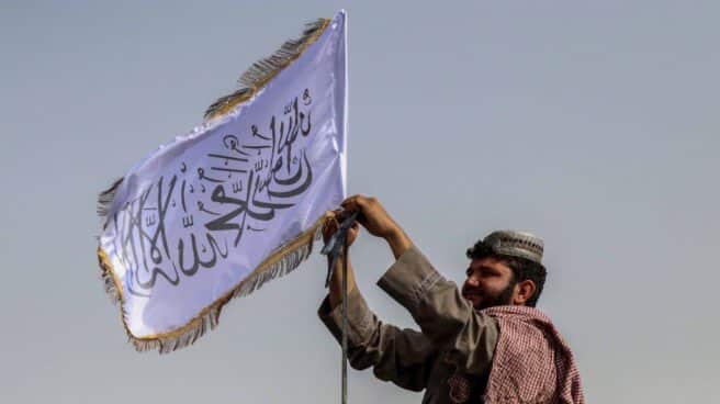 Un combatiente talibán iza la bandera del emirato en Kandahar. Un talibán coloca la nueva bandera de Afganistán en Kandahar
