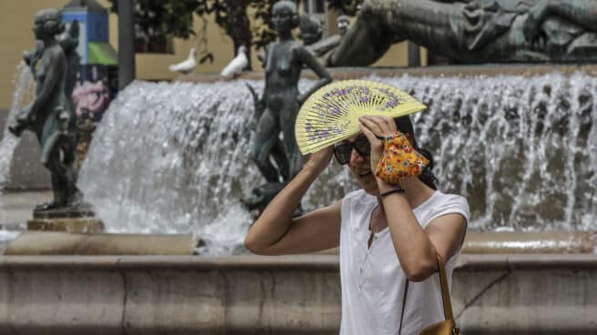 Alerta roja por calor en la Comunidad Valenciana y Murcia Una mujer se tapa la cabeza con un abanico para guarecerse de las altas temperaturas en Valencia.