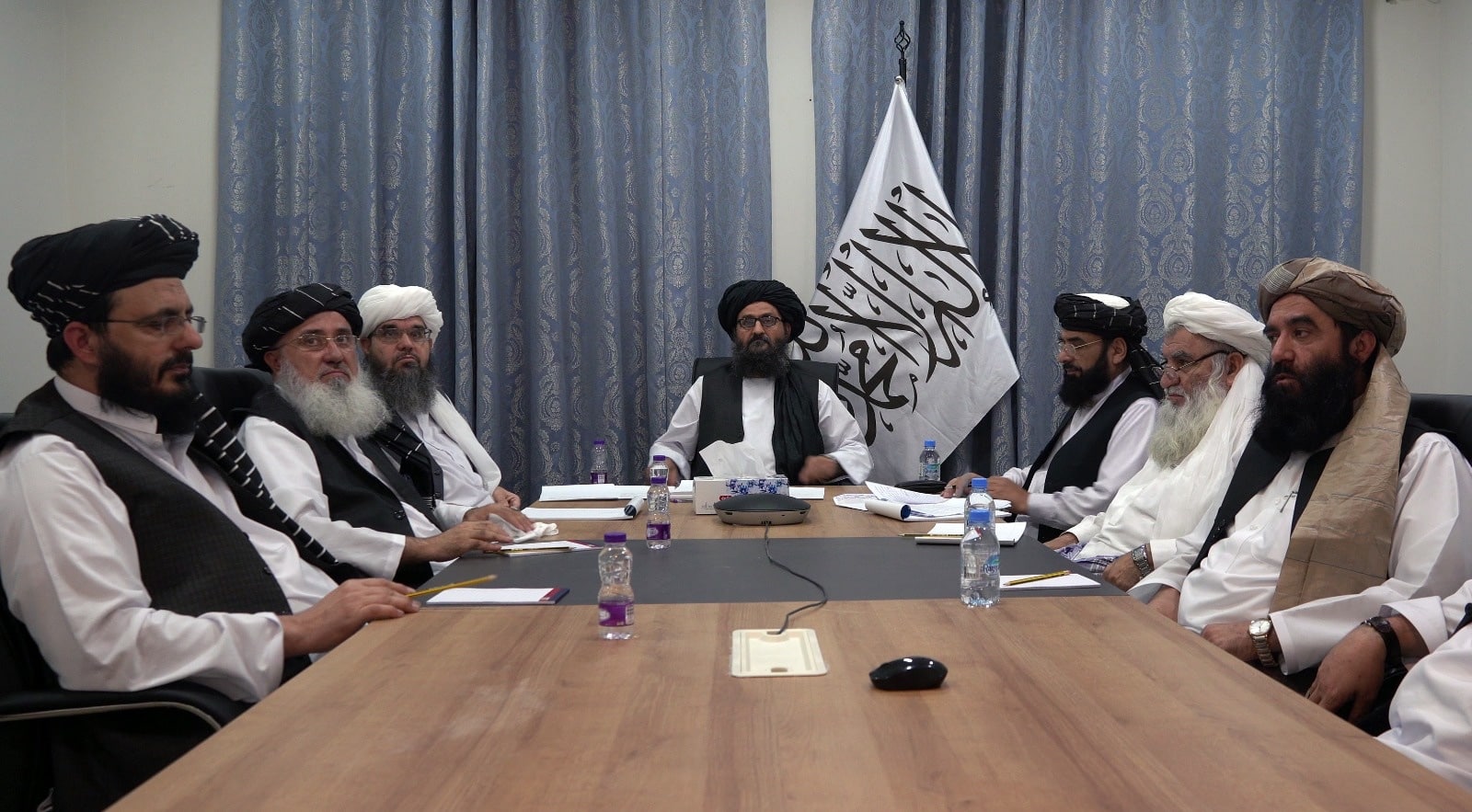 El mulá Abdul Ghani Baradar, junto a la bandera, talibán en una reunión
