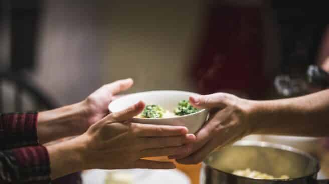 dietoterapia-plato dos personas se pasan un plato con comida saludable
