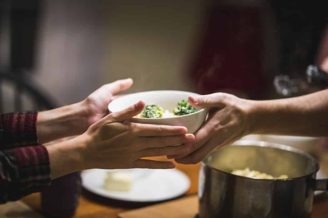 dos personas se pasan un plato con comida saludable