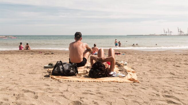 Dos personas en la arena en una playa observando el mar