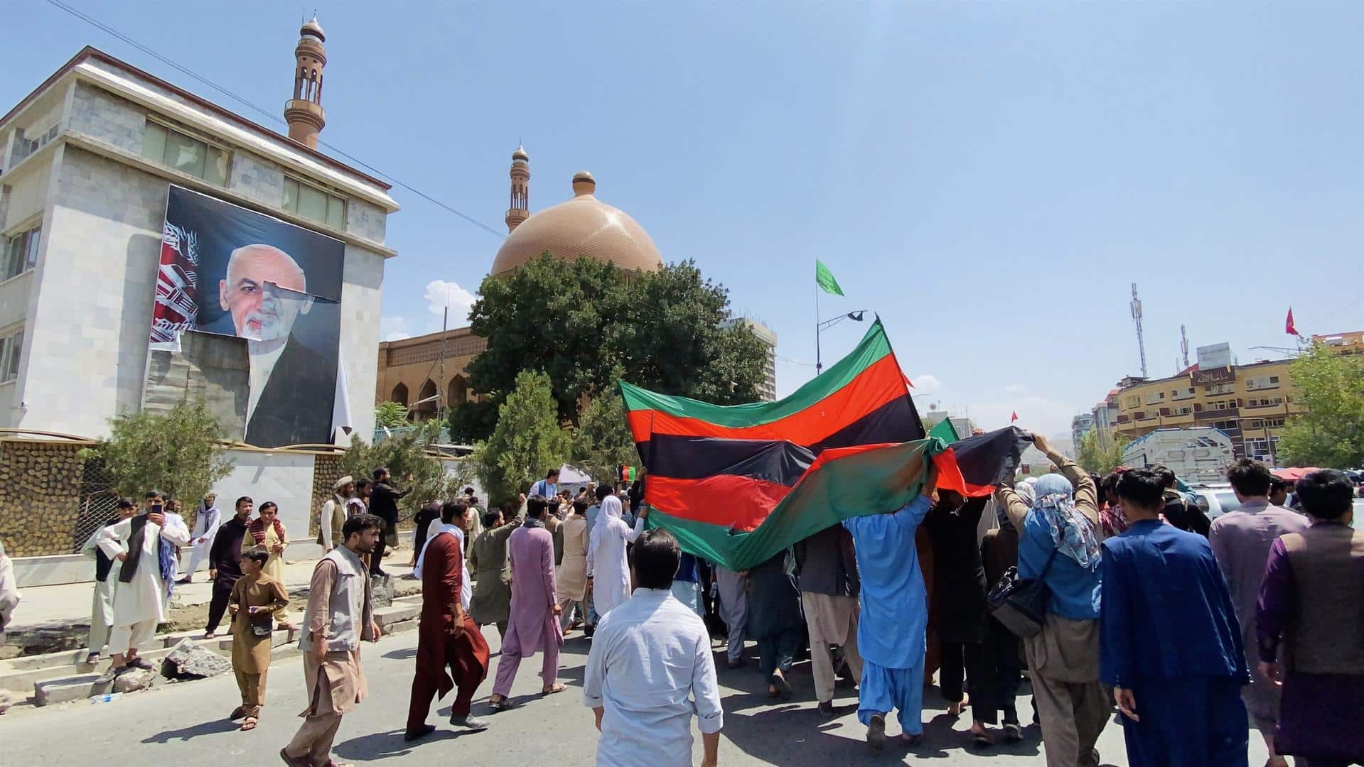 Afganos marchan por Kabul, frente a un mural del presidente huido Ghani, durante el Día de la Independencia.