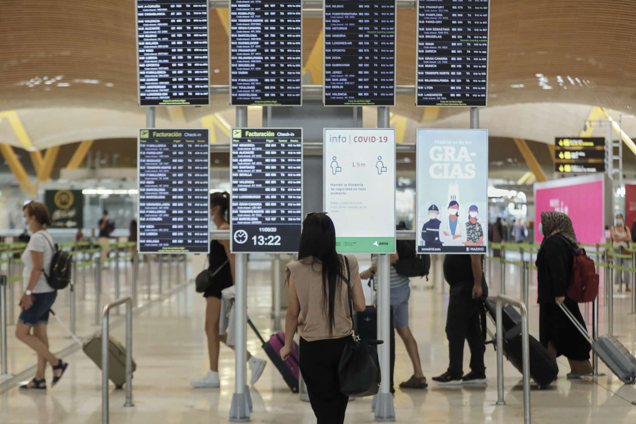 Pasajeros cerca de páneles informativos en la terminal T4 del aeropuerto Adolfo Suárez Madrid-Barajas.