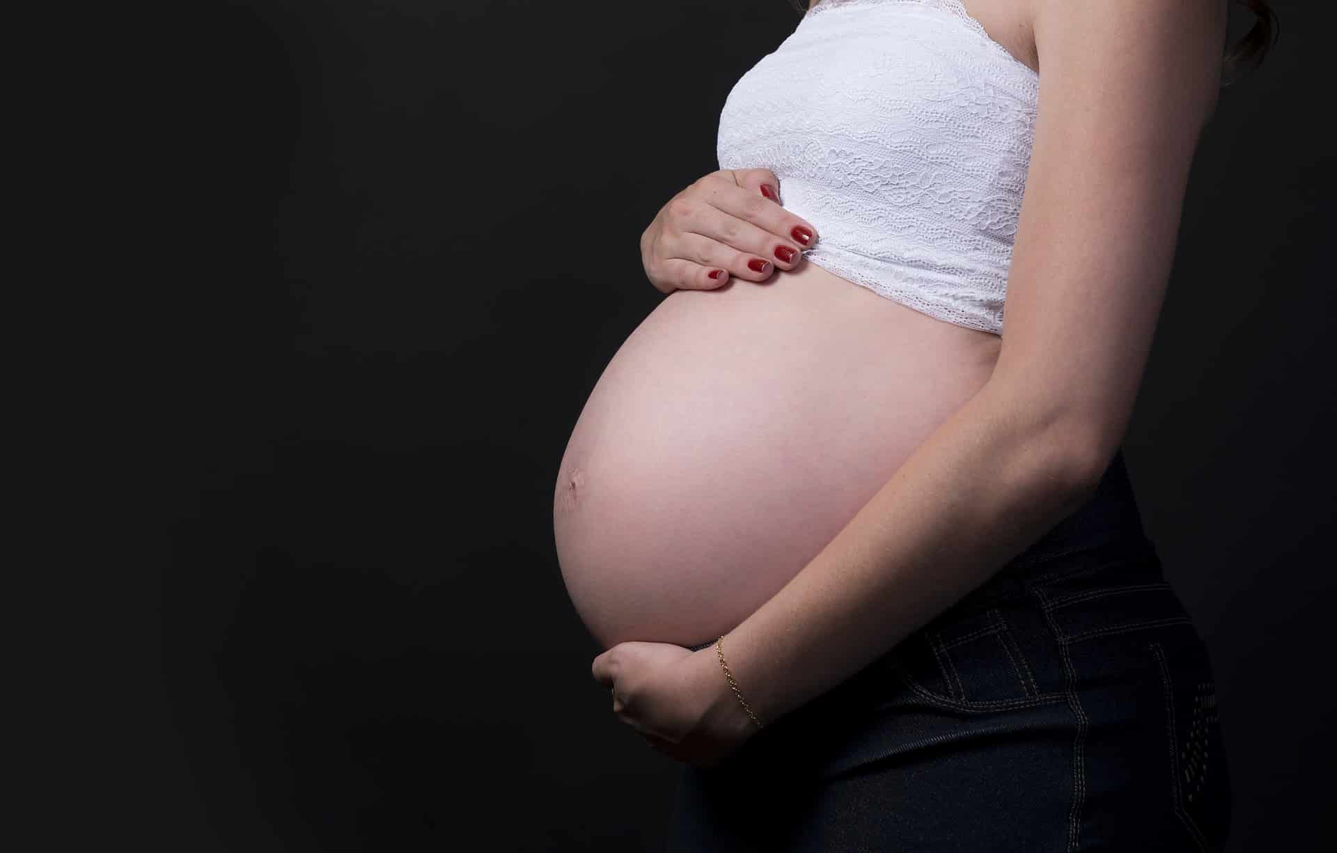 Una mujer embarazada se sostiene el vientre.