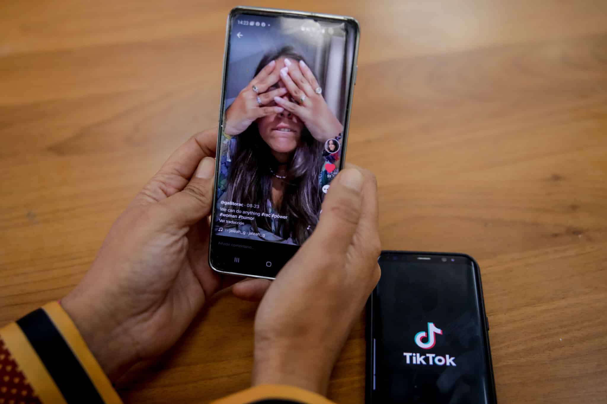 Una persona mira en su móvil el vídeo de una joven en la red musical Tik Tok