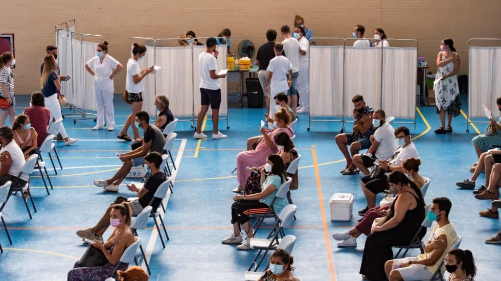 Multitud de jóvenes aguardan sentados tras recibir la vacuna contra el coronavirus, en el pabellón municipal de Espartinas (Sevilla).