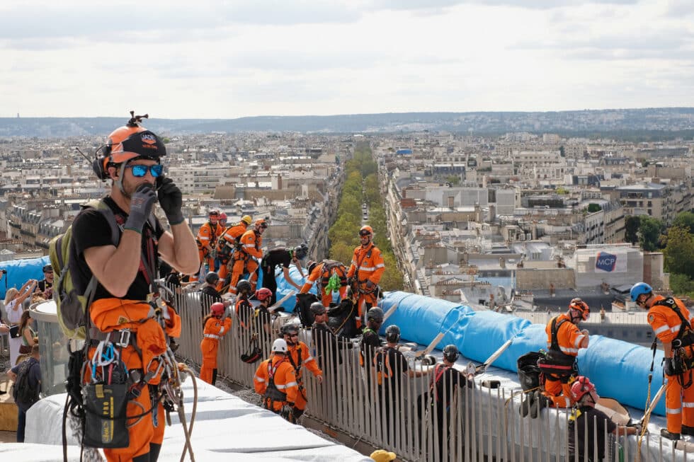 Trabajadores en el despliegue de paneles de tela frente a las paredes exteriores del Arco de Triunfo.