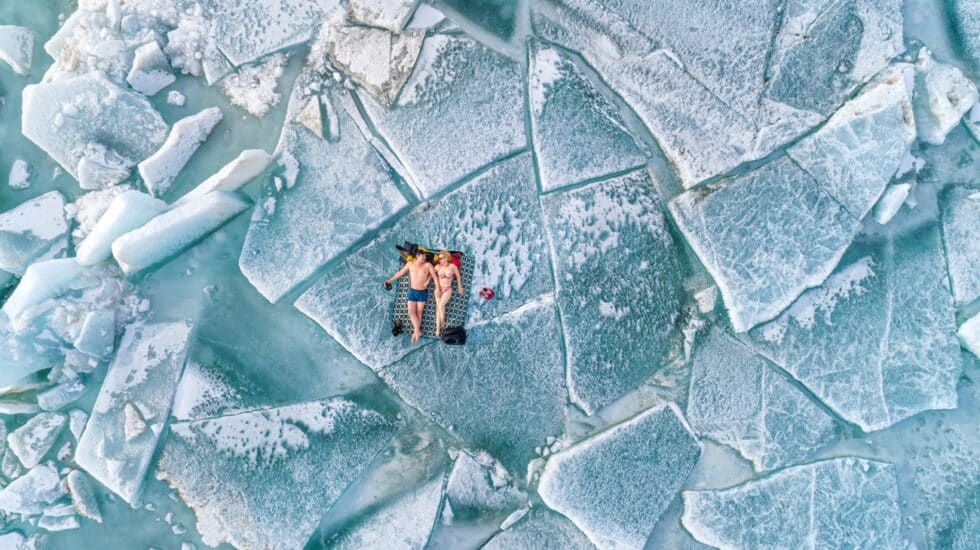 Fotografía vista de dron de una pareja tomando el sol sobre un bloque de hielo