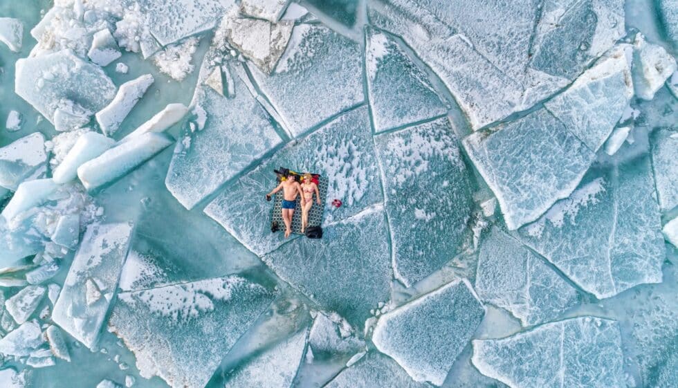 Fotografía vista de dron de una pareja tomando el sol sobre un bloque de hielo