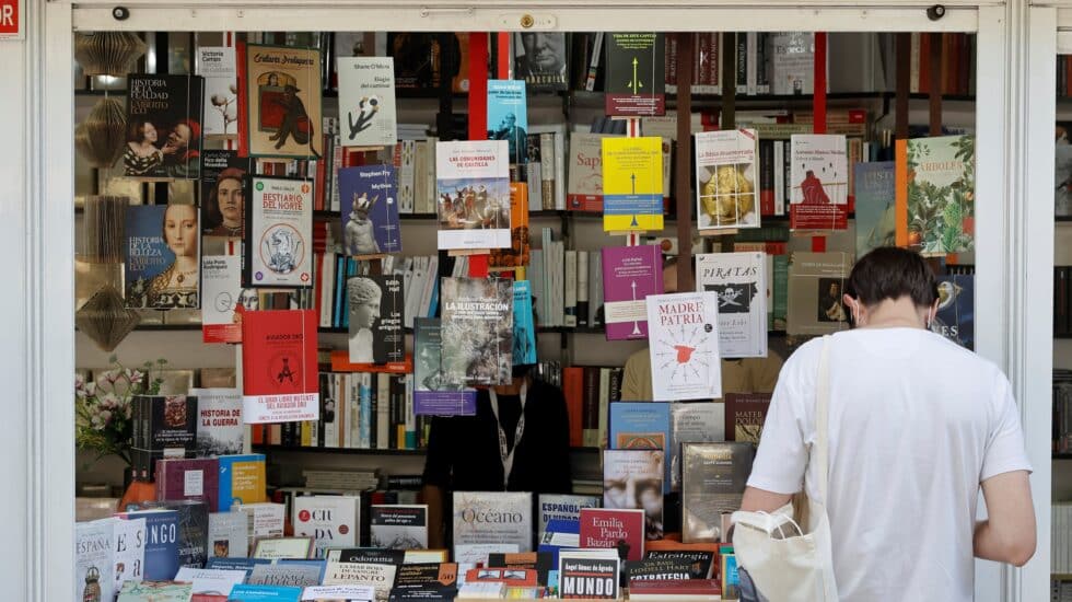Un hombre se interesa por un libro en la Feria del Libro de Madrid.