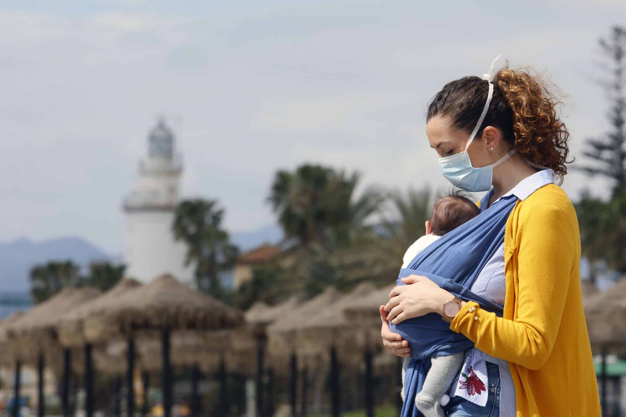 Una mujer protegida con una mascarilla da un paseo con su bebé en la playa de La Malagueta en abril de 2020.