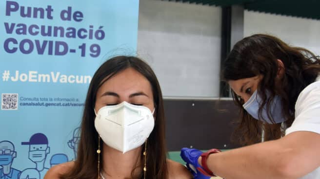 Mujer con mascarilla siendo vacunada por una sanitaria contra el Covid-19