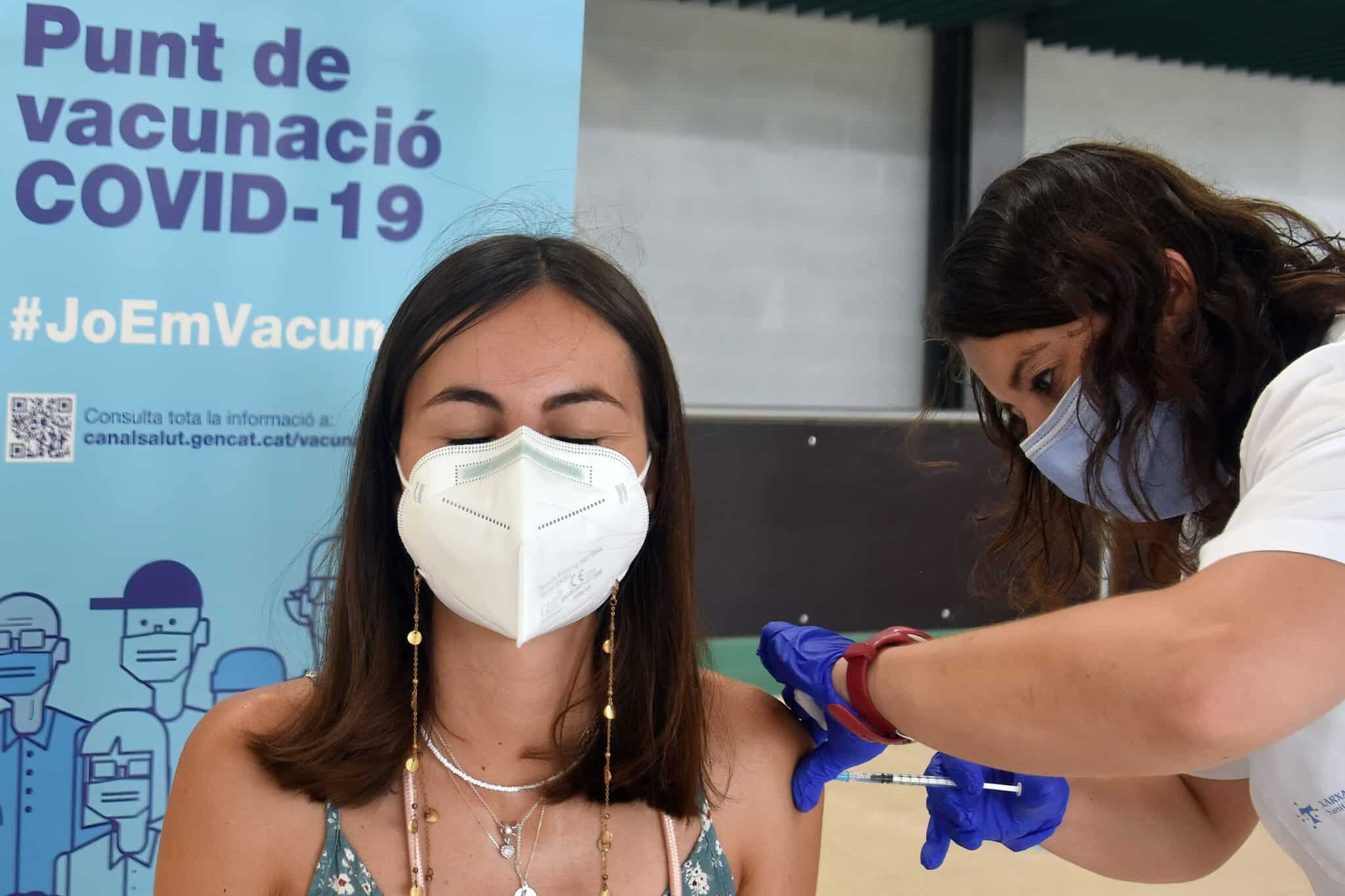 Mujer con mascarilla siendo vacunada por una sanitaria contra el Covid-19