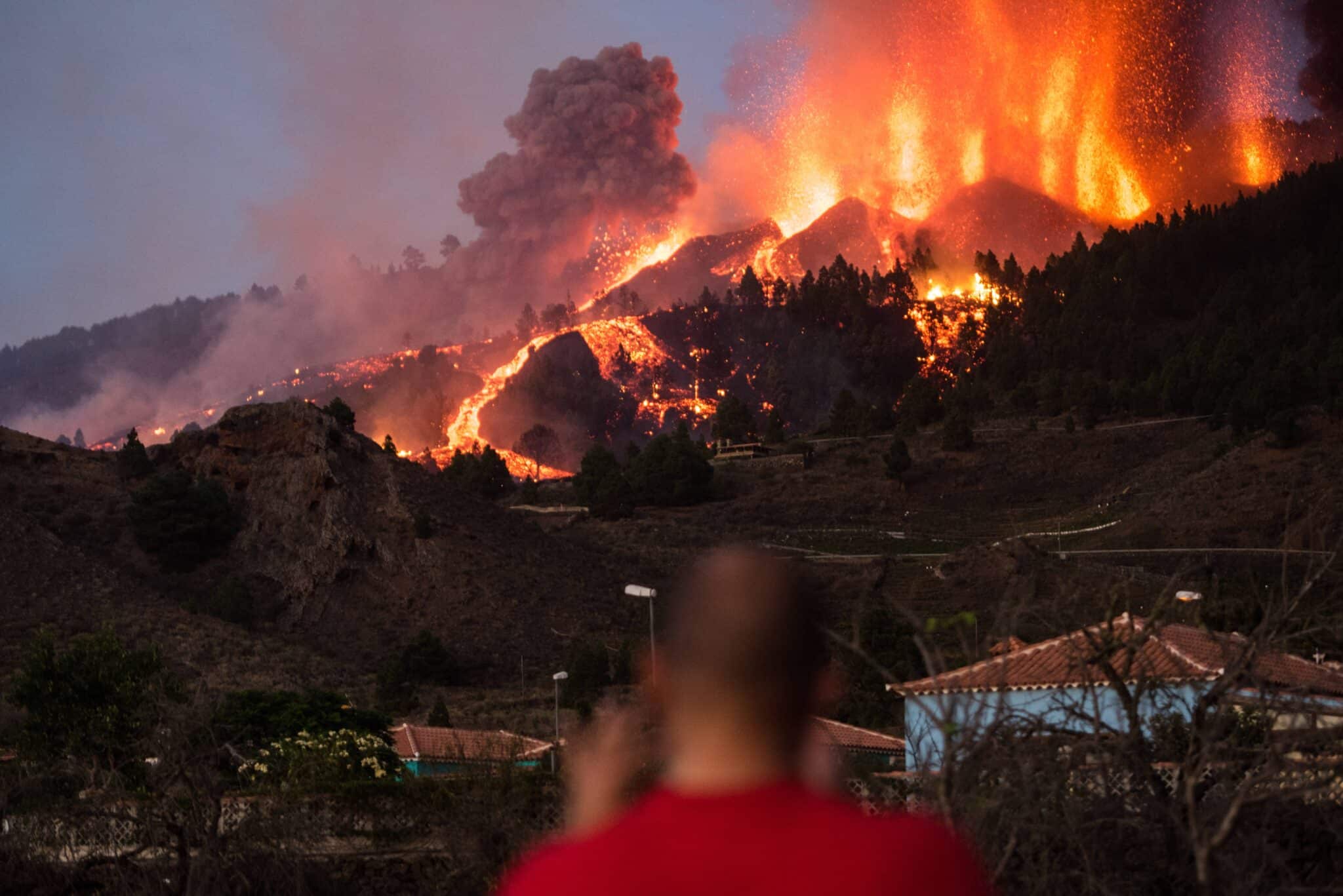 Imagen del Volcán de La Palma en plena erupción y una persona tomando fotografías del momento