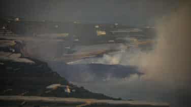 El viento aleja la nube de gases que deja la lava en el mar