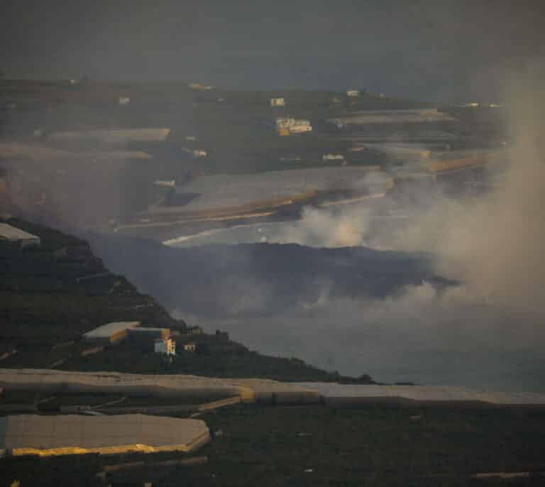 El viento aleja la nube de gases que deja la lava en el mar